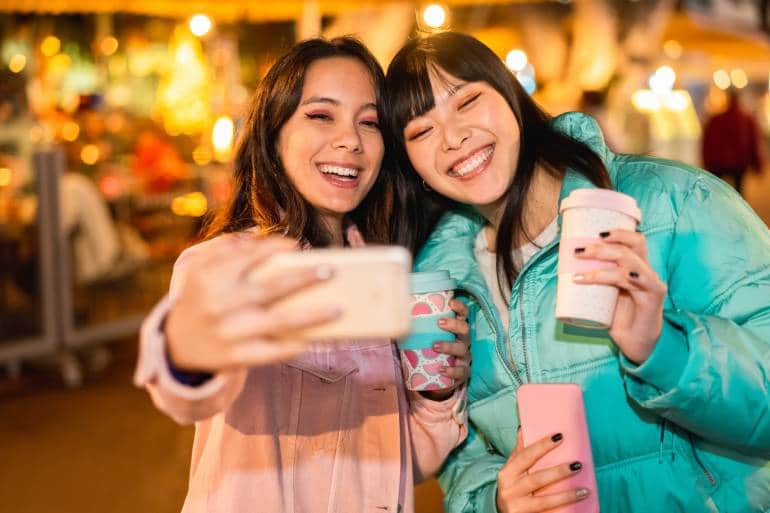 Happy asian friends making video with smartphone for social network app - Young women having fun with new technology trends - Friendship, tech and influencer concept - Focus on faces