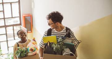 students carrying boxes of plants and knick-knacks as they move into a dorm