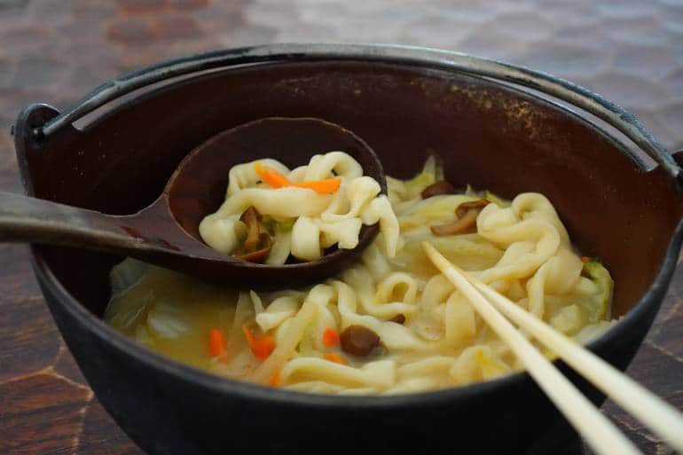 A bowl of houtou fudou noodles with a giant spoon and chopsticks ready to eat