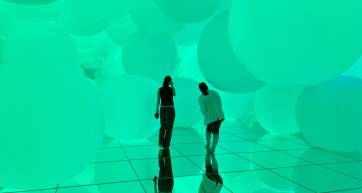 two people walk around teamLab Planets, the spheres room.