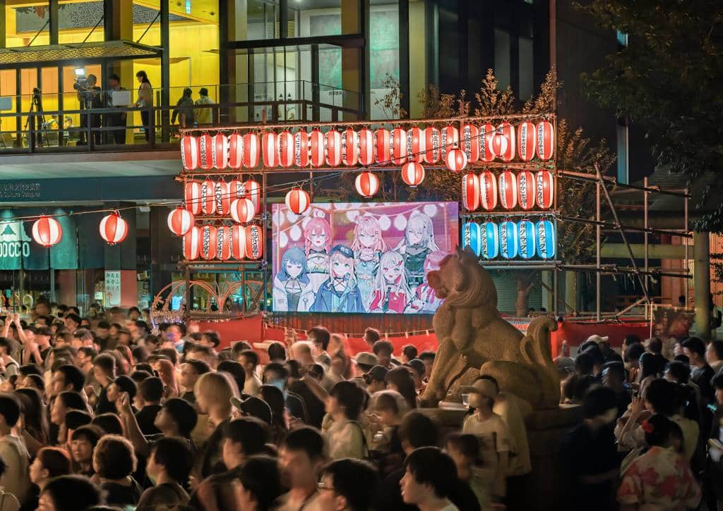 tokyo, akihabara - aug 11 2023: Crowd illuminated at night by lanterns aside a broadcast screen displaying manga characters during the Anime Song Bon Odori Dance Festival held in Kanda Myojin Shrine.