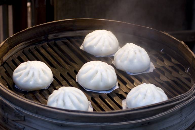 Nikuman buns with meat, steaming on a grill